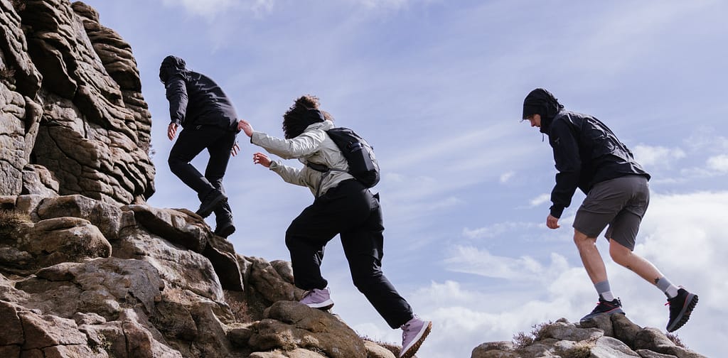 three people climbing hill with columbia sportswear backpacks