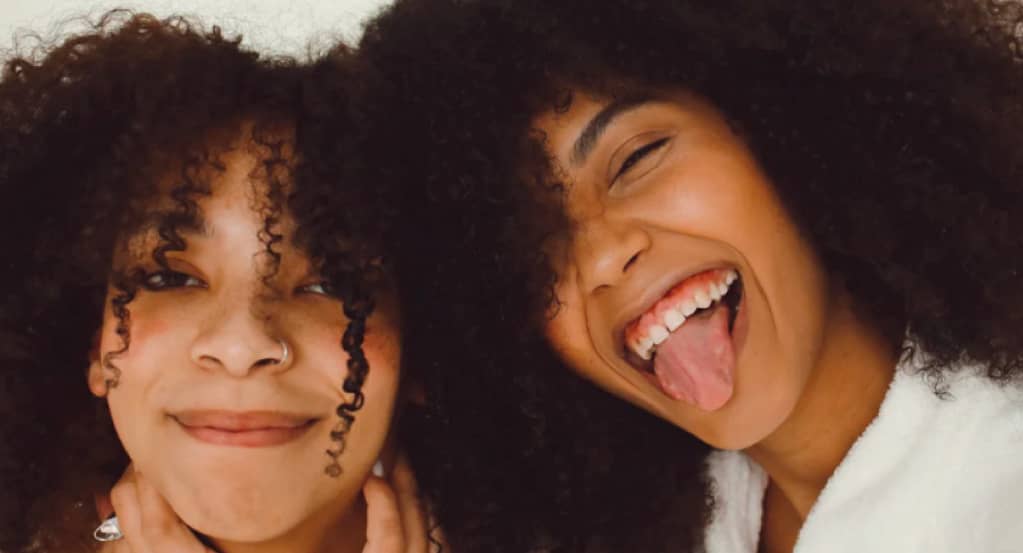 two women with afro hair smiling