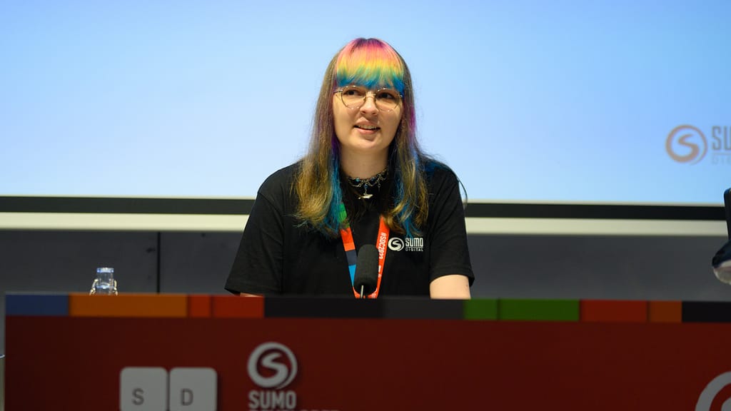 Nina Klos speaking at a conference. She is stood behind a lectern and speaking.